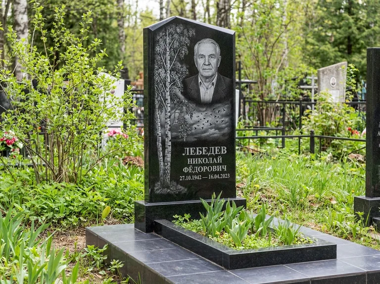 Памятник с гравировкой берёзы: вертикальная стела со скошенным верхом — берёза и стая птиц в небе, гранитный цоколь с тёмной плиткой, работа «Лебедев» в Саратове