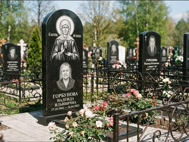 Памятник с гравировкой иконы: стела с арочным верхом и киотом под образ — гравировка образа Матроны Московской, гранитный цоколь с тёмной плиткой, работа «Ковалёв» в Саратове