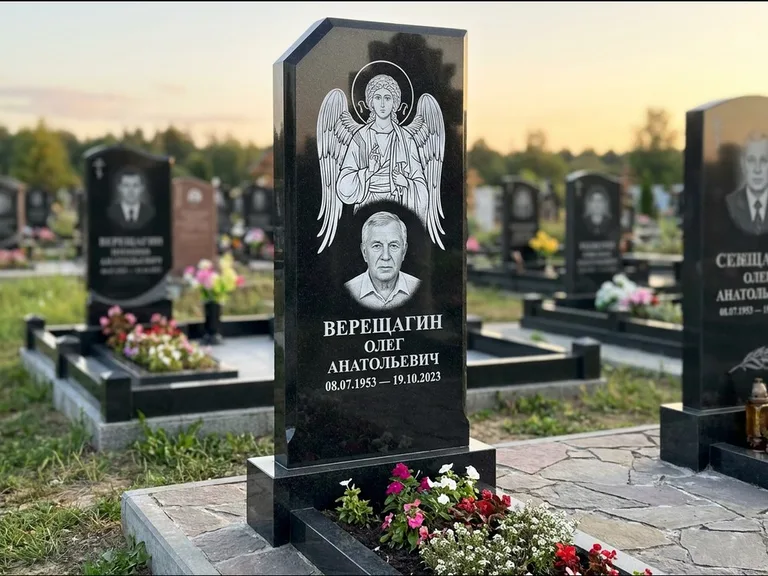 Памятник с гравировкой иконы: стела с резным навершием и нимбом в золоте — гравировка образа Спасителя, высокие разросшиеся туи полукругом, работа «Мельникова» в Саратове