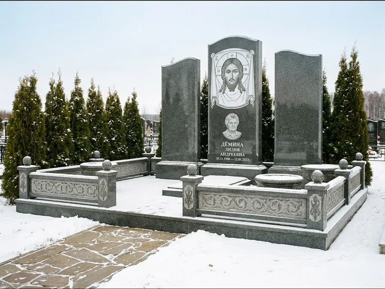Памятник с гравировкой иконы: узкая вертикальная стела-пилон с ликом — икона в резной рамке-киоте, открытая лужайка без ограды, работа «Одинцов» в Саратове