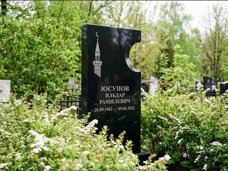 Мусульманский памятник с гравировкой мечети: стела с боковым вырезом в форме полумесяца — гравировка минарета с полумесяцем, низкие кусты спиреи в цвету, работа «Юсупов» в Саратове