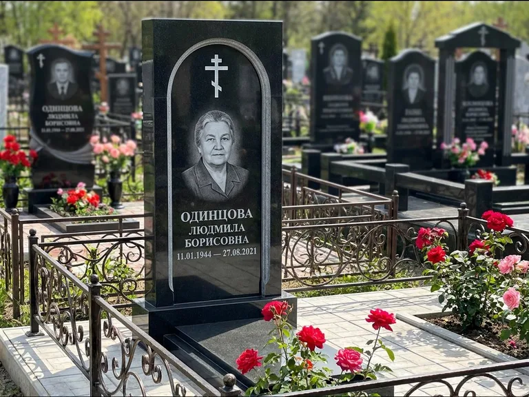 Памятник из чёрного гранита — скромная невысокая стела с крестом с терновым венцом, работа «Лаврентьева» в Саратове