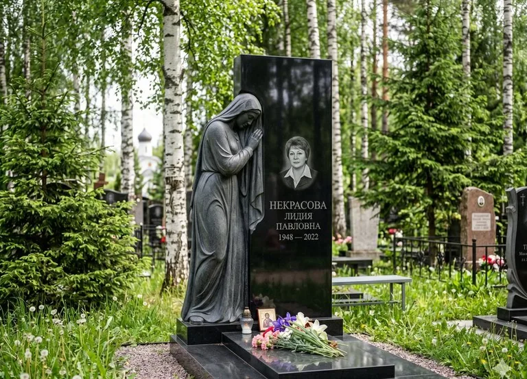 Гранитная фигура скорбящего мужчины у чёрной стелы в Саратове